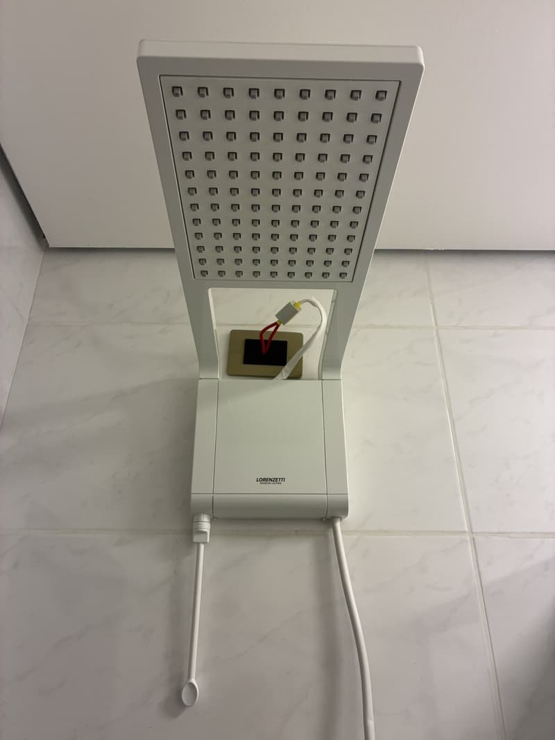 Chuveiro elétrico branco instalado em banheiro azulejado
